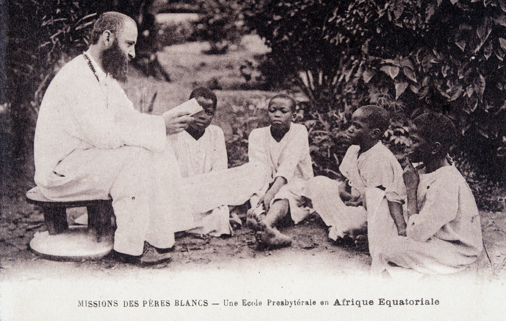 Missionnaire en Afrique : un membre de l'Ordre missionnaire des Peres Blancs enseignant a des enfants dans une ecole d'Afrique equatoriale. Carte postale du debut du 20eme siecle ©Collection Sirot-Angel/leemage